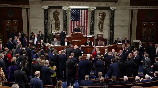 Photo of the US House of Representatives, with representatives crowding into the well of the House