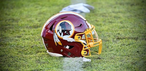 Photo of a maroon football helmet sitting on a football field that bears a profile image of a Native American man