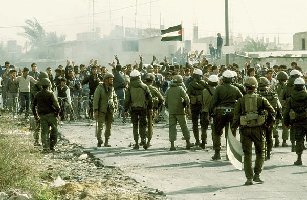 Photo of Israeli police and military confronting Palestinian protesters across a barbed-wire barrier