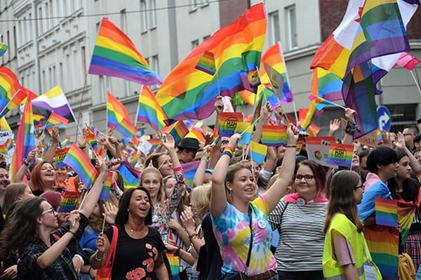 Photo of marchers, mostly women, waving rainbow Pride flags