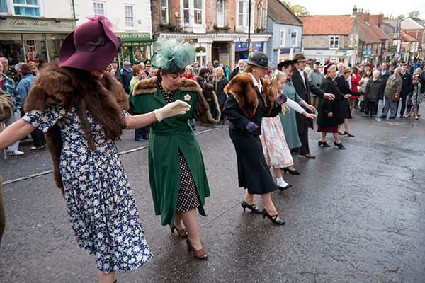 People in 1940s-era clothing dancing the Hokey Pokey (Hokey Cokey) in the streets of Pickering, England, 2013