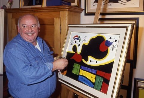 Photo of a middle-aged man standing in front of an abstract painting