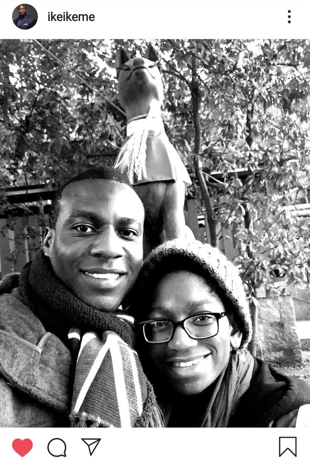Screenshot of an Instagram post. Black and white photo of my brother and I smiling underneath a dog or fox statue at a Japanese temple. We are dressed for cold winter.