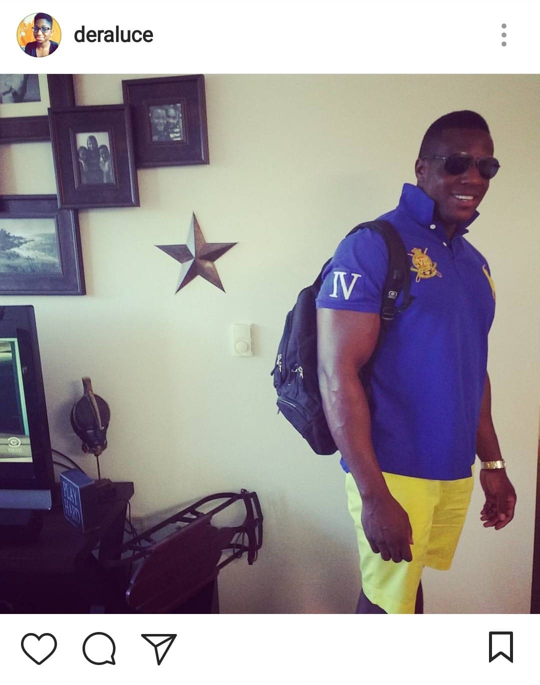 Screenshot of an Instagram post. My brother is looking like a boss in his shades, bright yellow shorts, and royal blue polo with a popped collar. He is at home, standing near framed photos of his kids.
