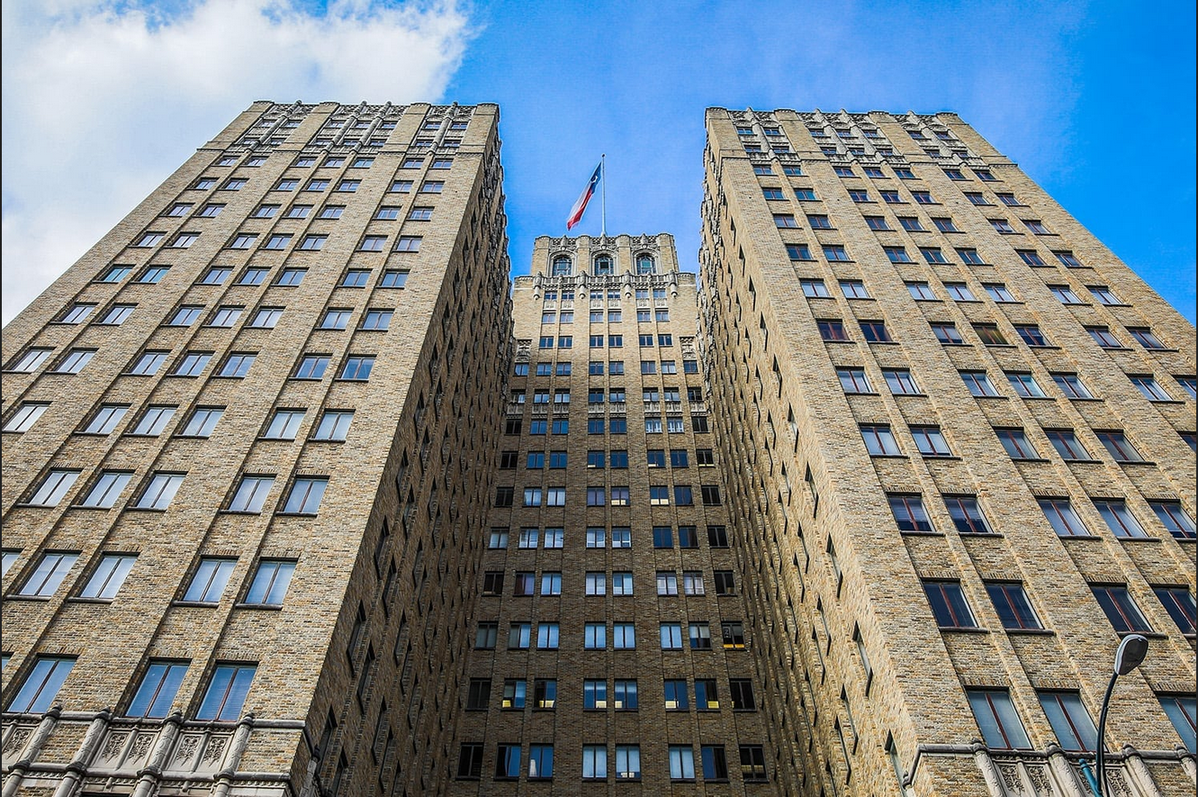 Photograph of front of 1928 21-storey brick-clad high rise building, from ground perspective, looking straight up.