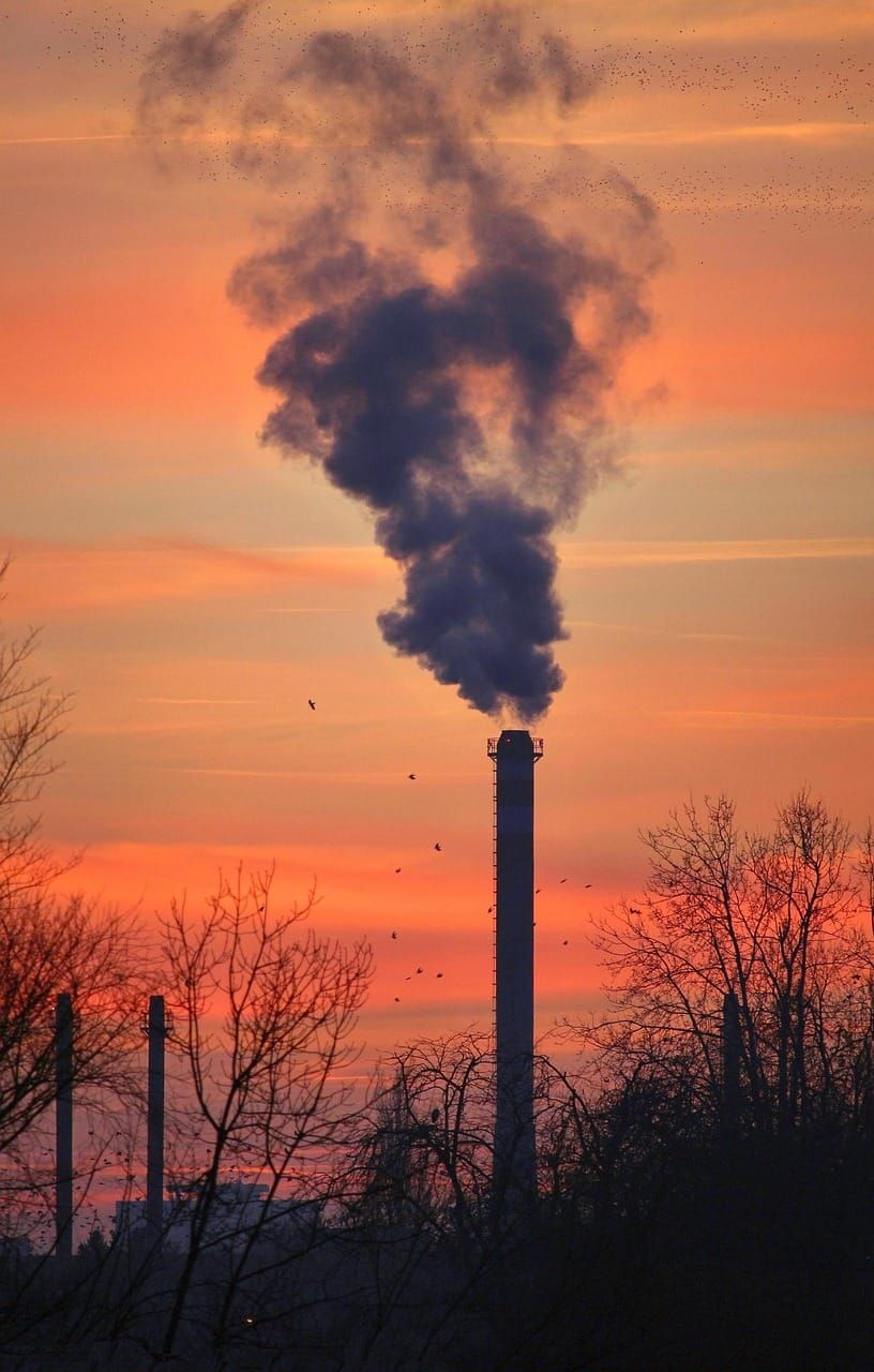 Gas well flaring off excess methane against an orange sunset.