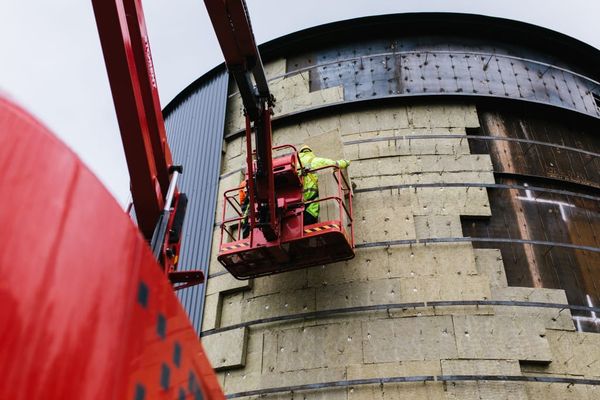 Insulation and claddidng being added to a large cylinrical steel tank that is under construction