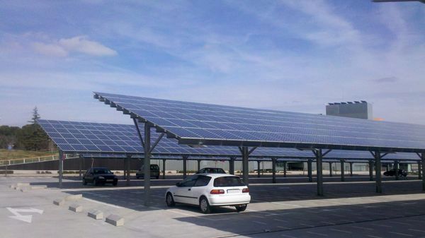 Parking lot with large tilted solar photovoltaic panels shading the car parking stalls