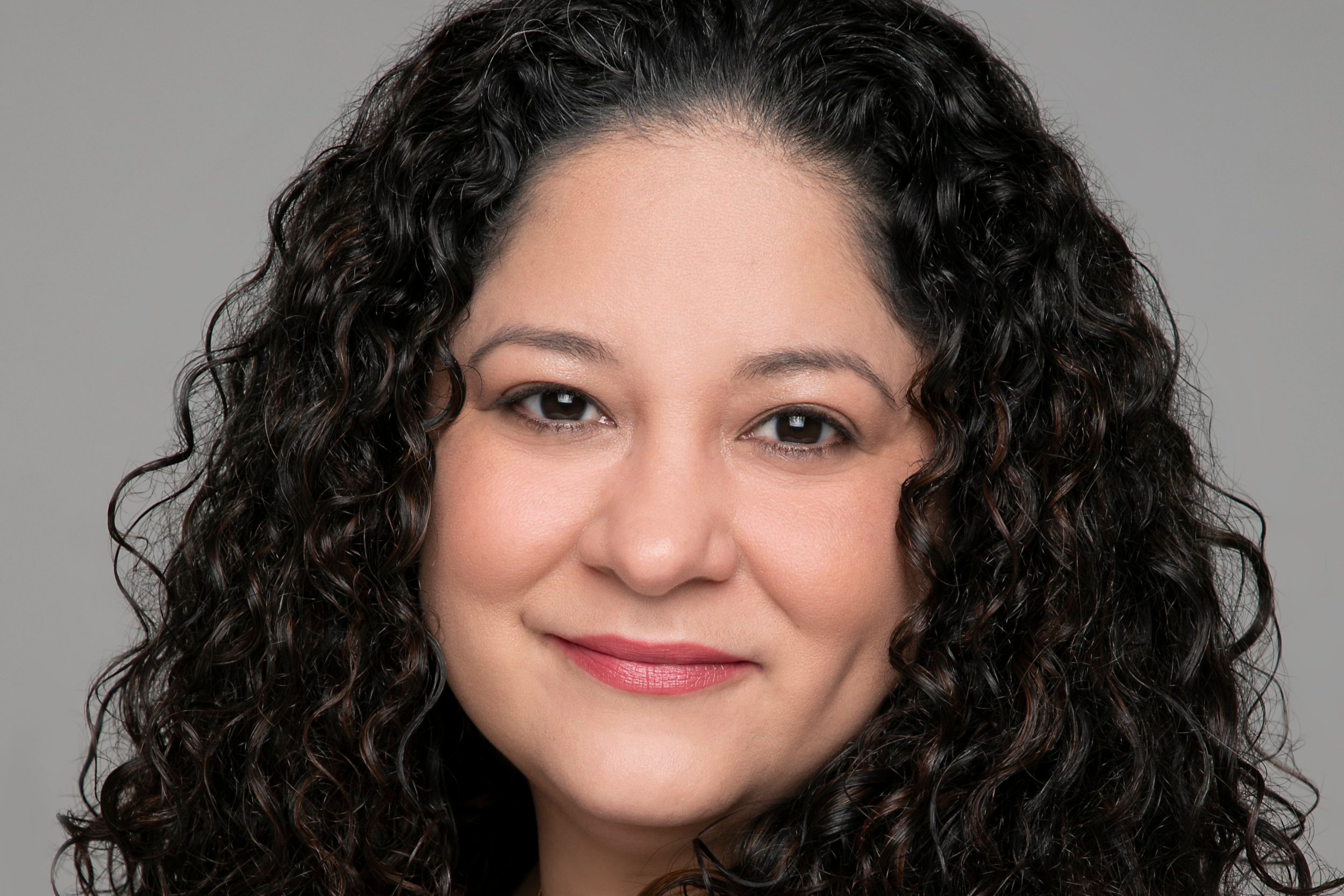 A close-up portrait of Nicole Gomez, smiling towards the camera.