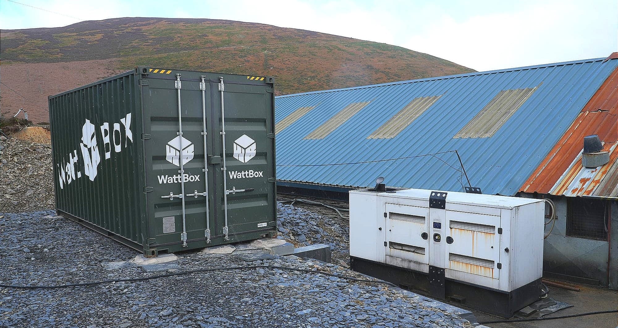 A Wattbox sitting next the to an older generator, new power source meeting the old power source. 