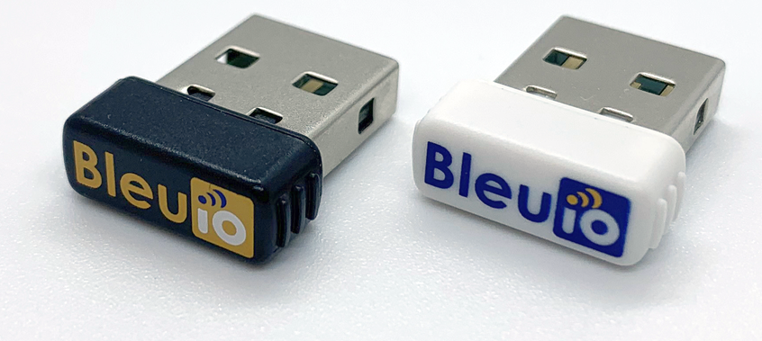 Photograph of two BleuIO Standard USB dongles side by side, one in a black case and one in a white case.