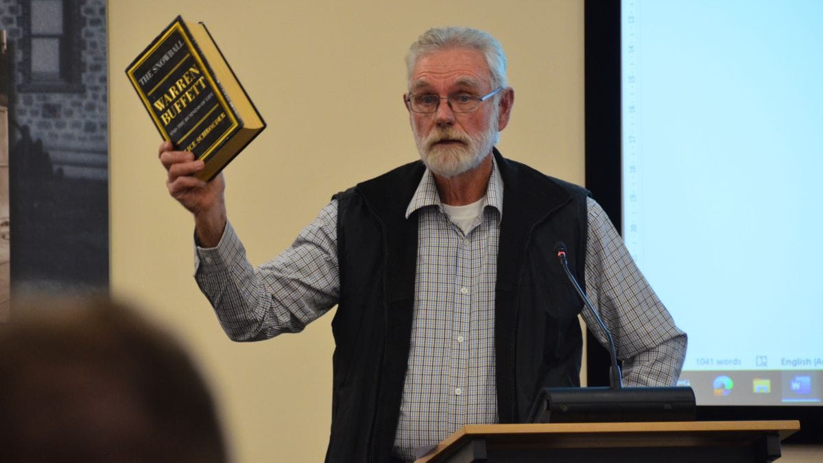 Jerry Wilson holds up a Warren Buffett book at a Murray Bridge council meeting.