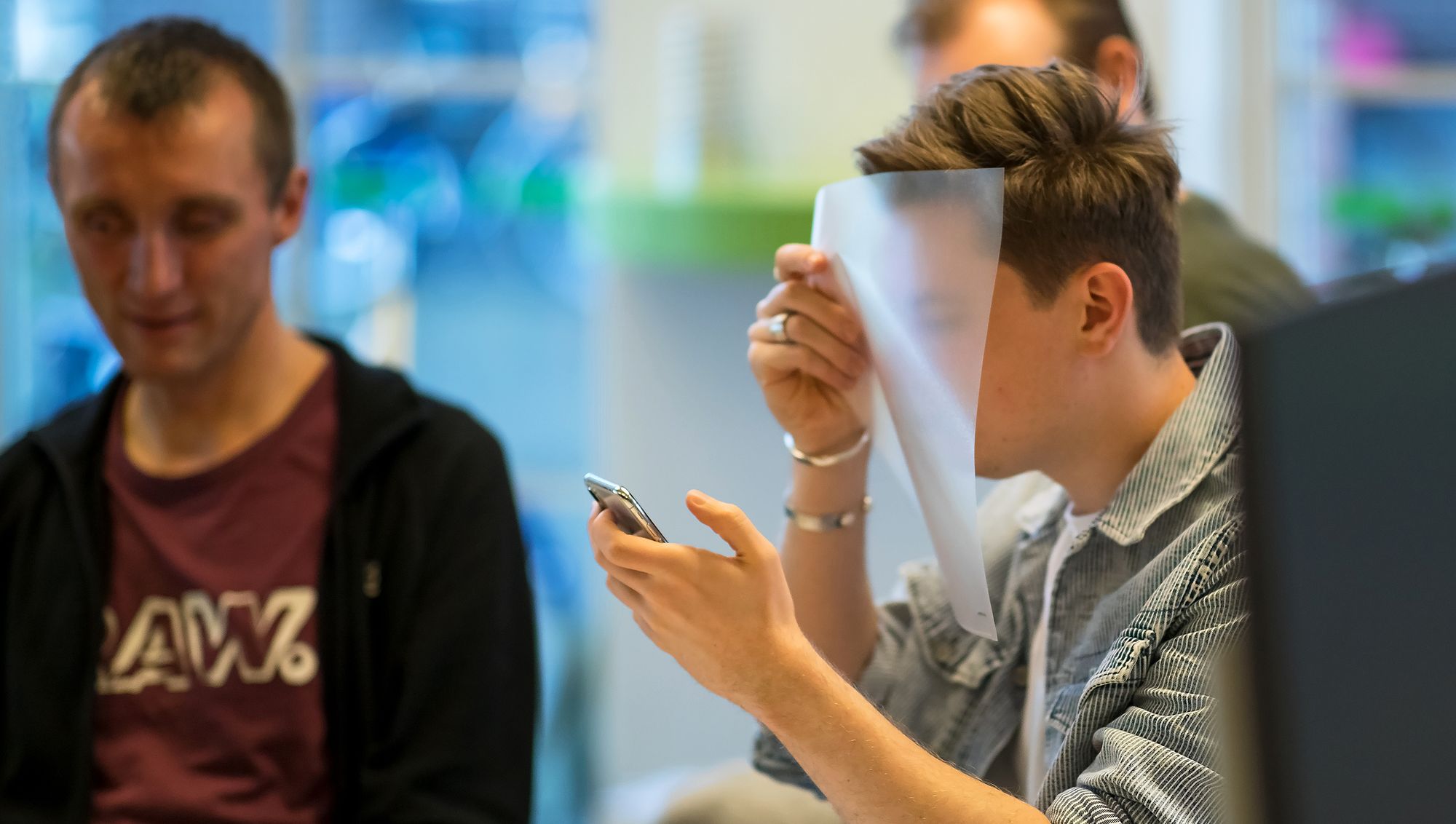 Ontwerper kijkt door doorzichtig mapje naar z'n mobiele telefoon om de ervaring van slechtzienden na te bootsen.