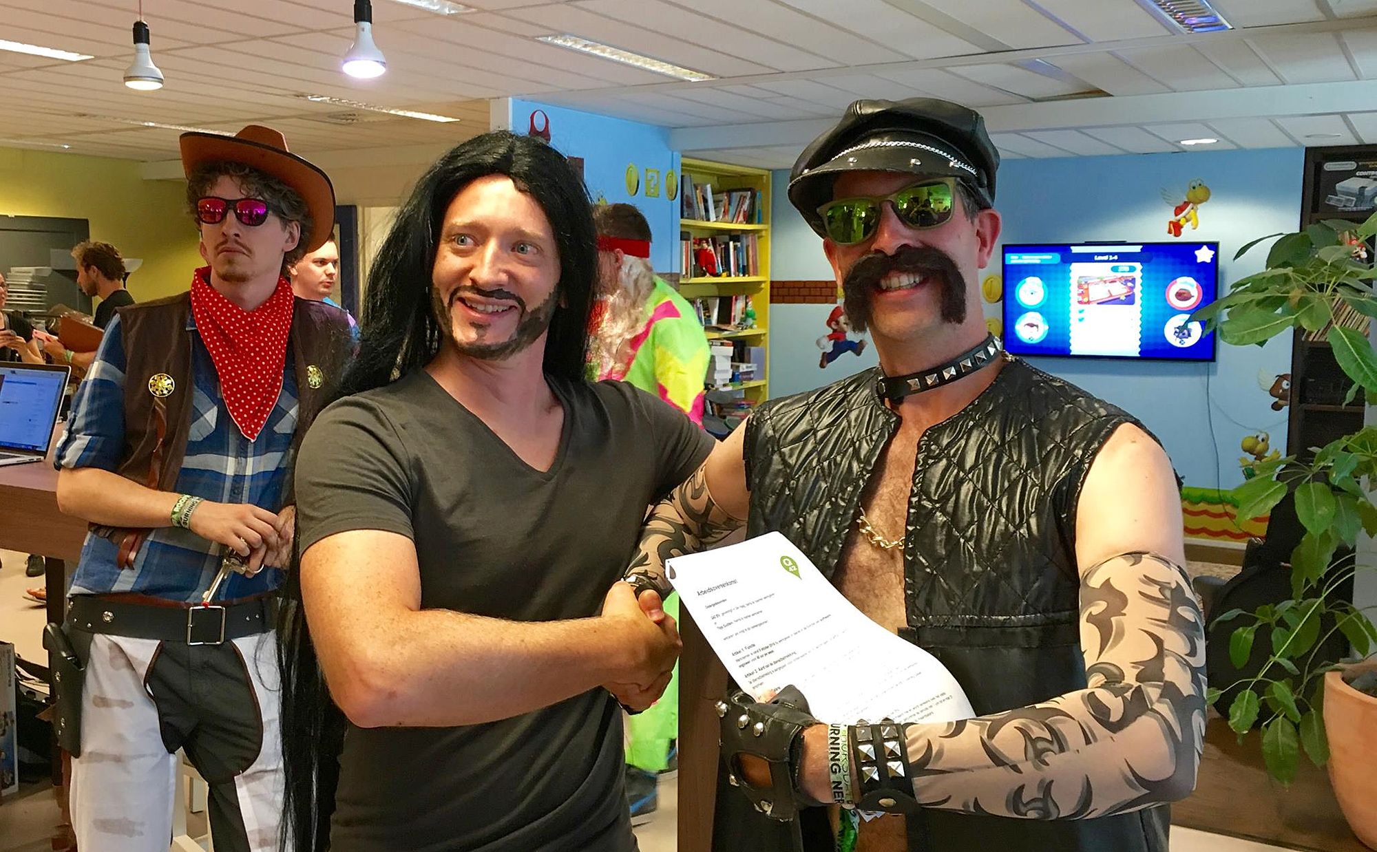 Eén van de partners van internetbureau Q42 feliciteert een developer met diens vaste contract, terwijl ze beide verkleed zijn.