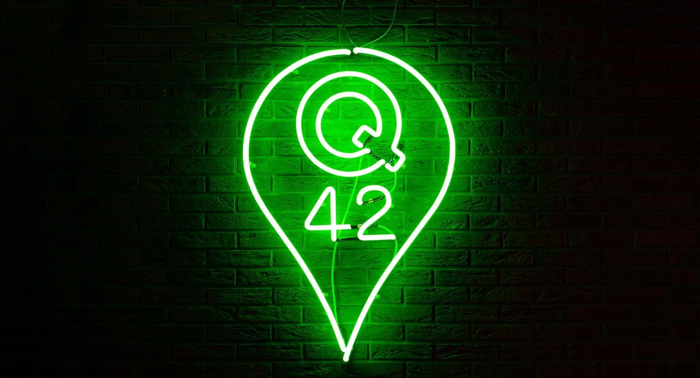 Foto van het Q42-logo als neonversie gemonteerd aan een bakstenen muur.