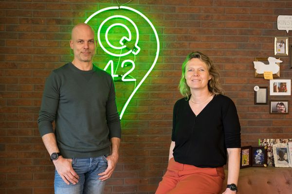 Stef Brooijmans en Wietske Rodenhuis met op de achtergrond een groen neonlogo van Q42.