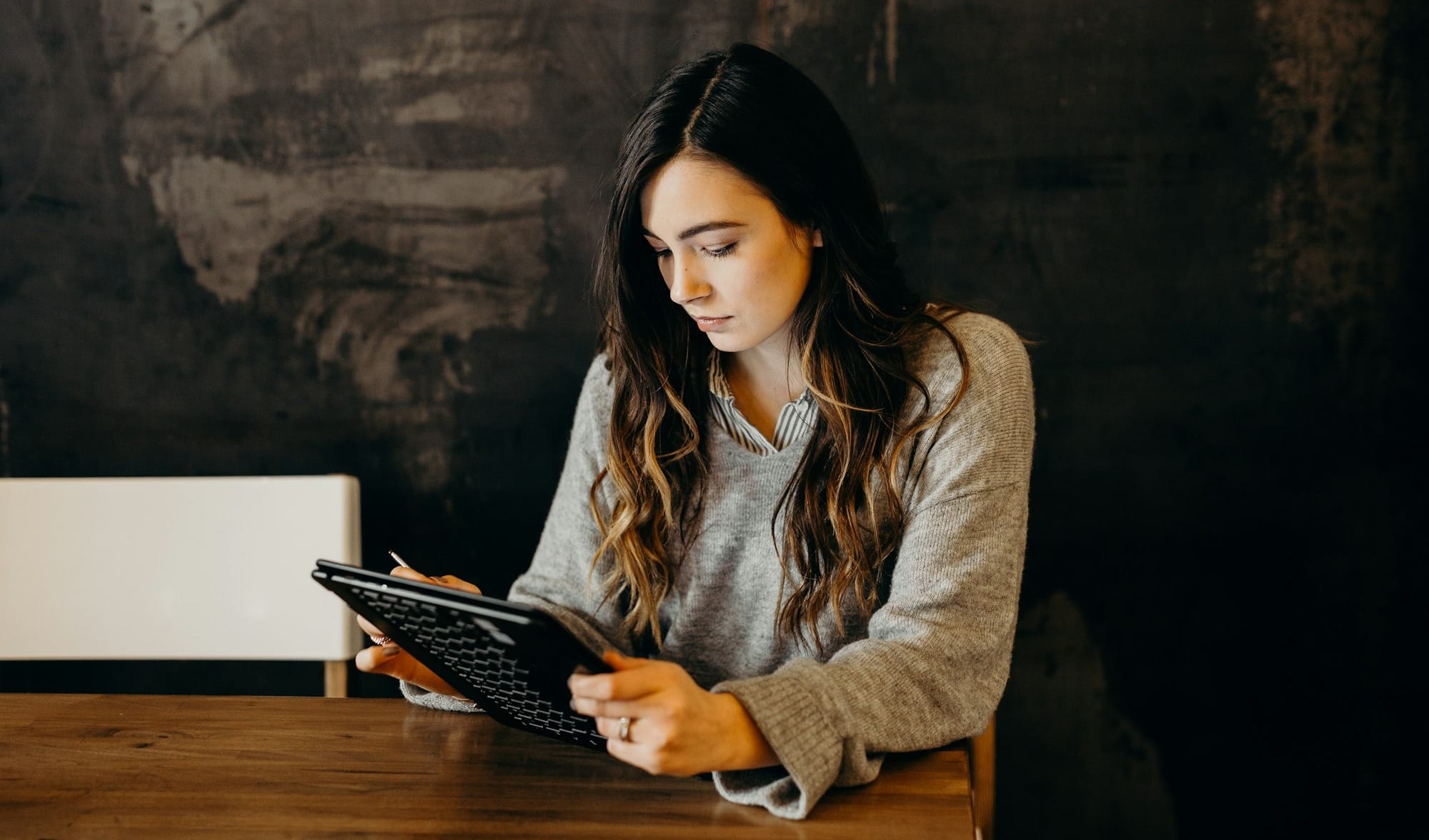 woman wearing white dress shirt using holding black leather case on brown wooden table