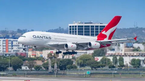 A Qantas Airways Airbus A380 descends at Los Angeles International Airport, with the city in the background