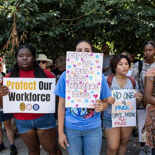 People hold signs at a rally calling on Congress to restore Temporary Protected Status (TPS) for Haitians