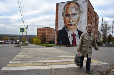 A woman crosses a road in front of a mural depicting Russian President Vladimir Putin in Kashira, Russia, southeast of Moscow, on Oct. 16, 2017.