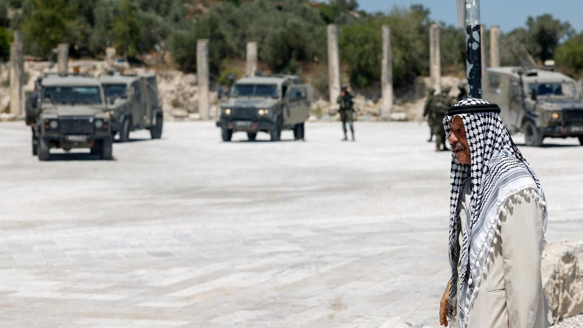 A Palestinian man walks near Israeli troops at the archaeological site of Sebastia, in the occupied West Bank (29 June 2026)