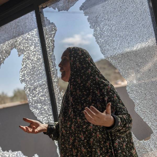 Palestinian Hanan Hamayei gestures as she stands near the shattered glass of her home following a reported attack by Israeli settlers, in the Israeli-occupied West Bank village of Turmus 'Ayya, on October 19, 2026.