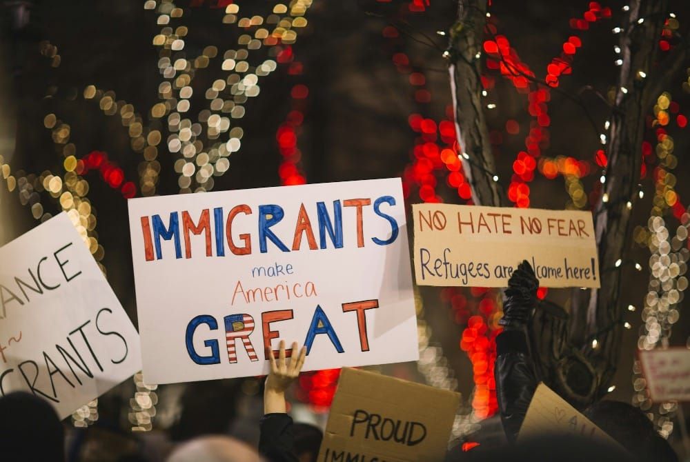 Immigration protest signs being held up by protesters at a rally.