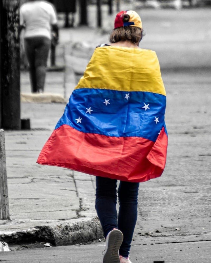 A woman walking down the street wrapped in a Venezuelan flag.