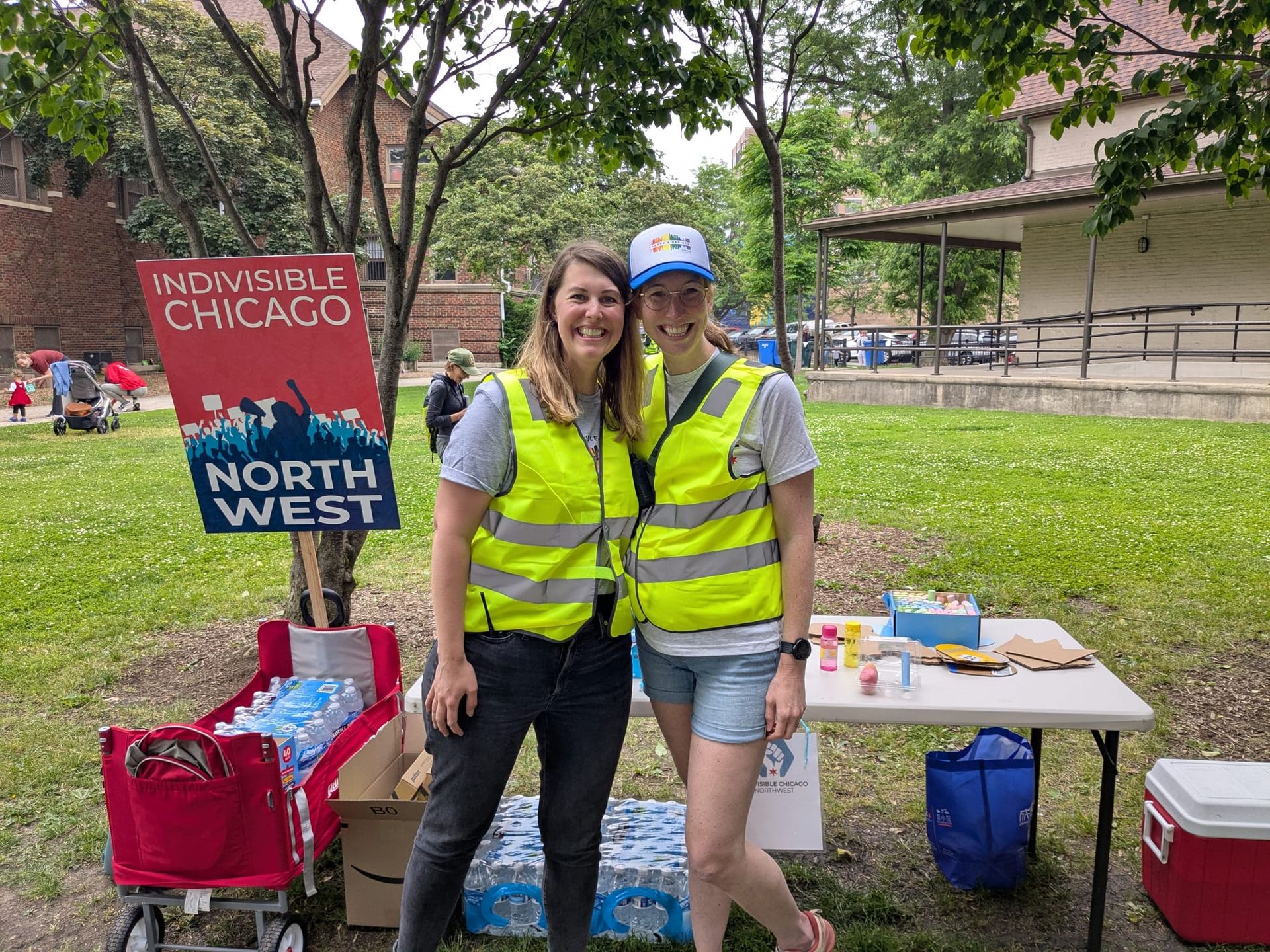 Parent Group leaders Alison and Kate in yellow vests in front of a volunteer table.