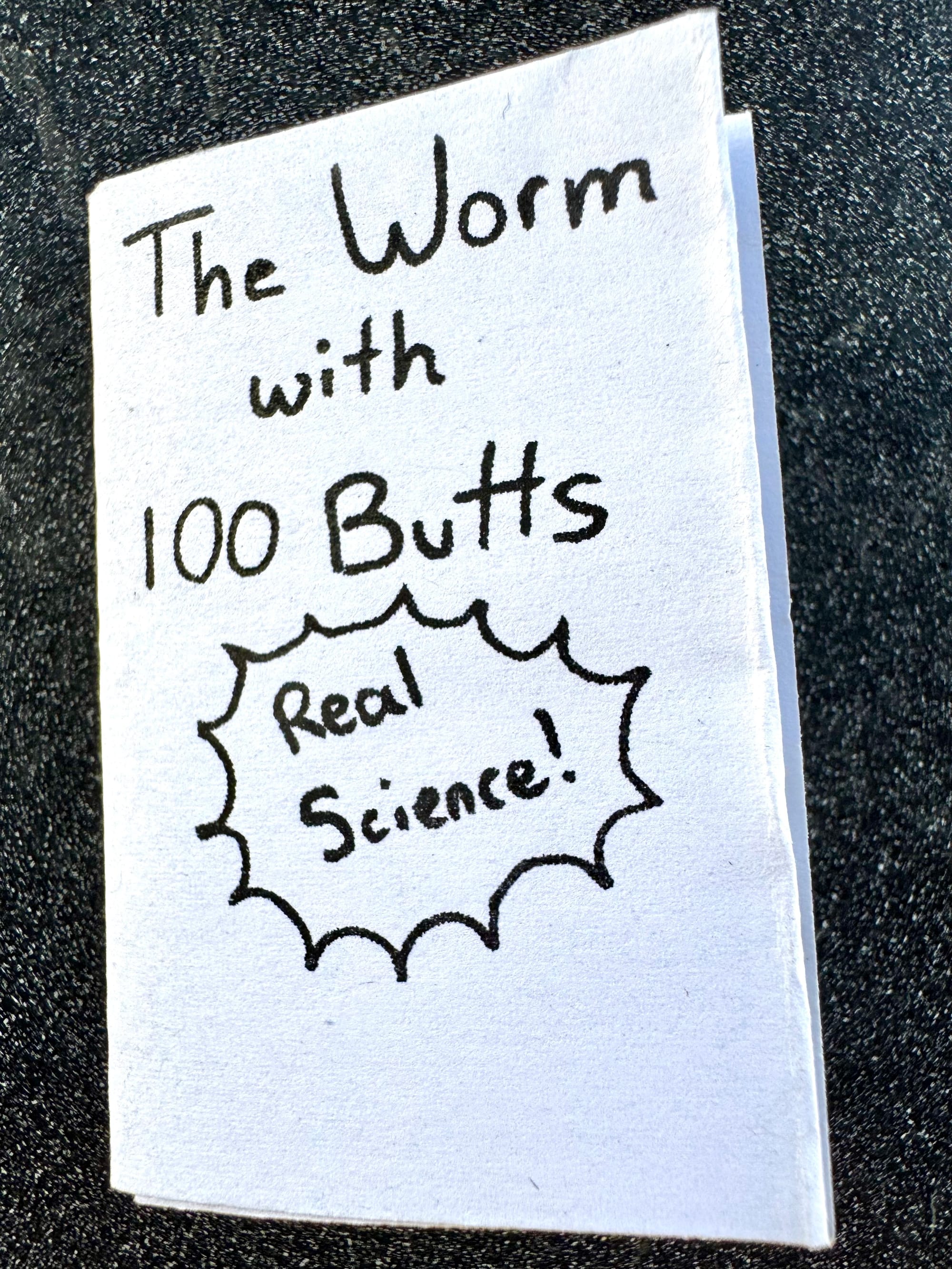 Photo of the cover of a zine. "The Worm with 100 Butts. (Real Science!)"