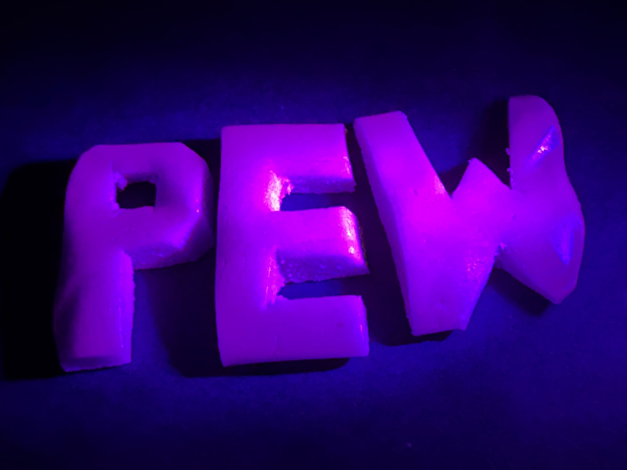 Magenta glowing version of the previous taffy candy, now carved into the capital letters PEW