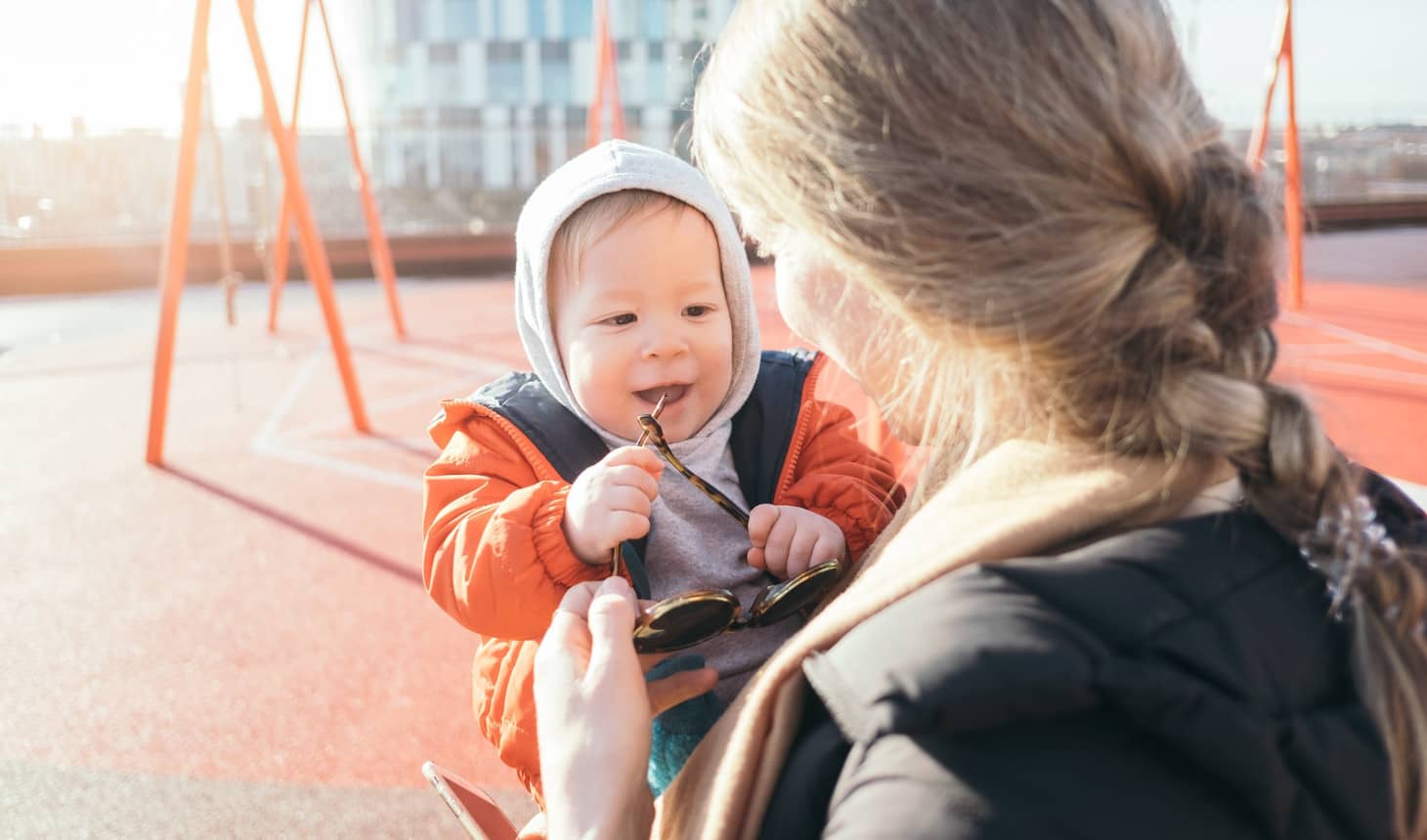cargando a un bebé que le coge las gafas a su mamá