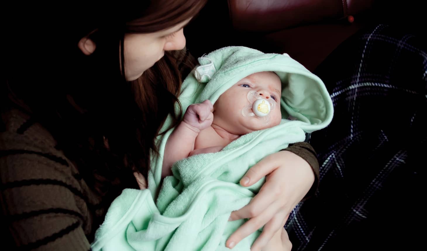 mamá acunando a un bebé que lleva chupete