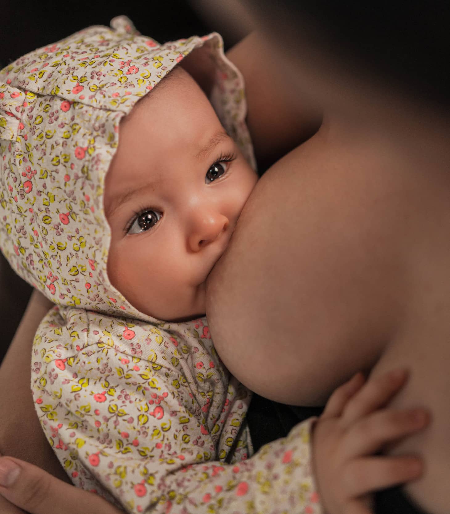 bebé con capucha mamando mirando a su mamá