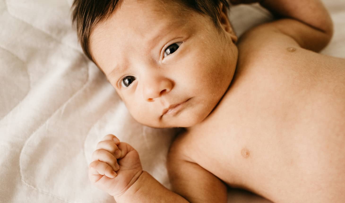 bebé recién nacido tendido con la manita arriba