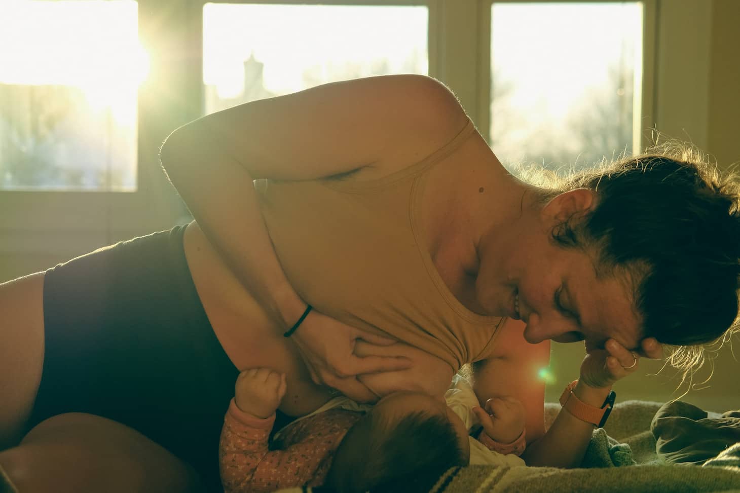 mama que da de mamar poniéndose por encima del bebé