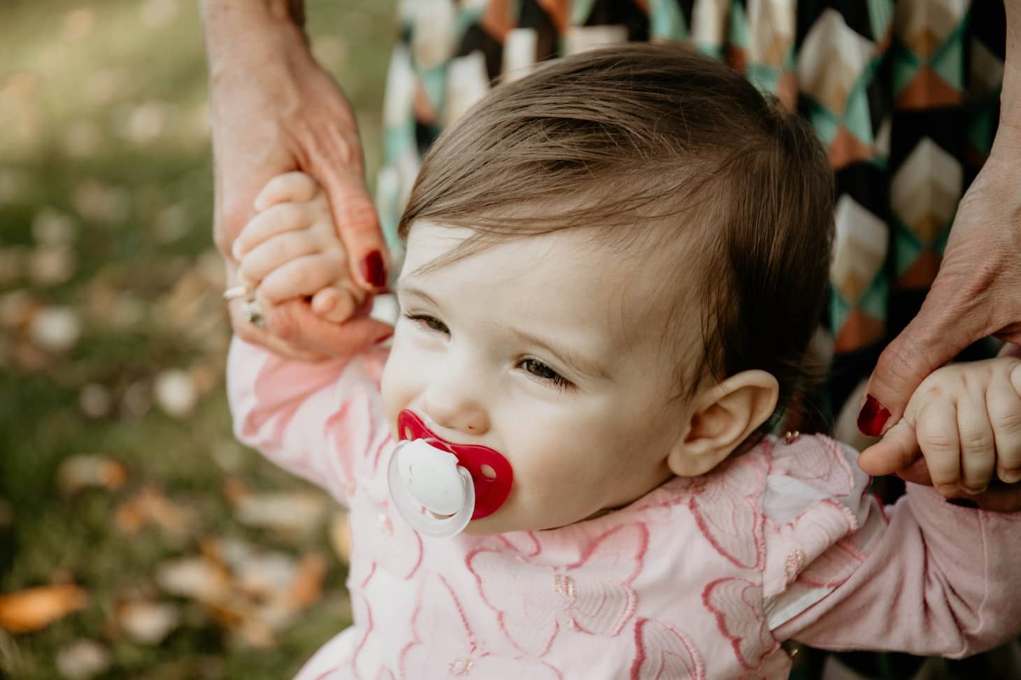 bebé con un chupete que da sus primeros pasos