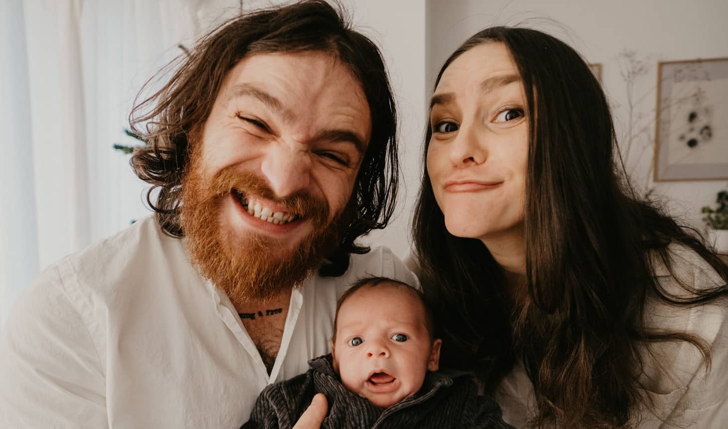 un recién nacido con mamá y papá que ponen caras