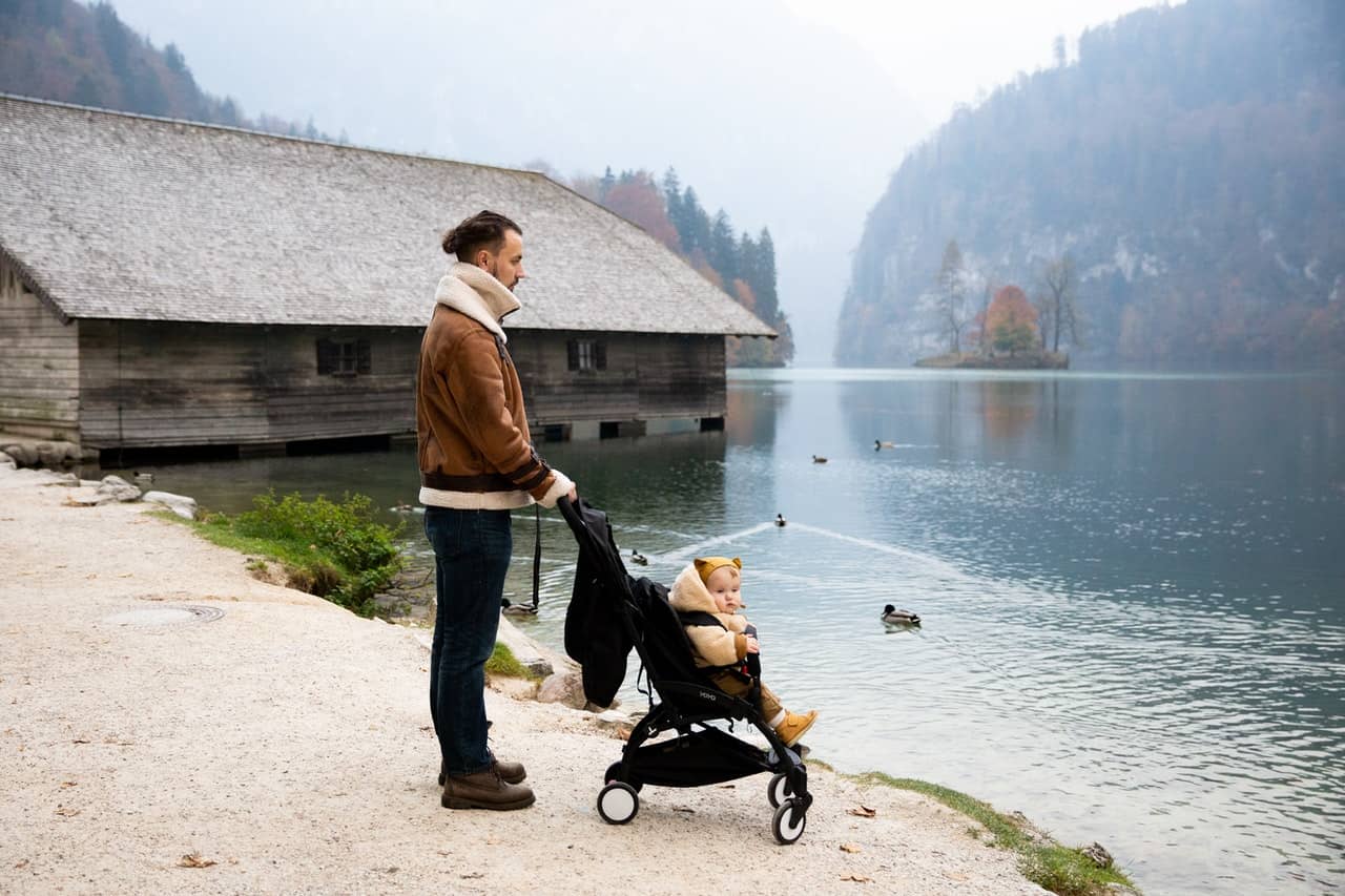 un bebé en un carrito y su papá mirando a un lago