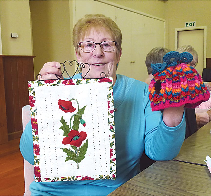 A member of the enthusiastic knitting group, Jan McNeil of Yarragon holds a wall hanging and a knitted tea cosy made in preparation for an event in May next year.