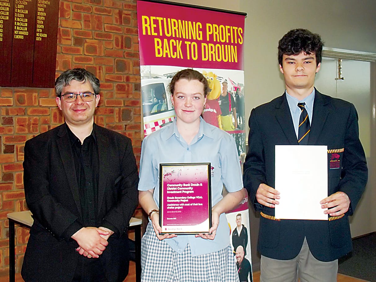 Bridget Wagner and Declan Sellick from Drouin Secondary College's VCAL project team working to fund a new bus shelter in the town receive community bank financial support from director Rob Celada.