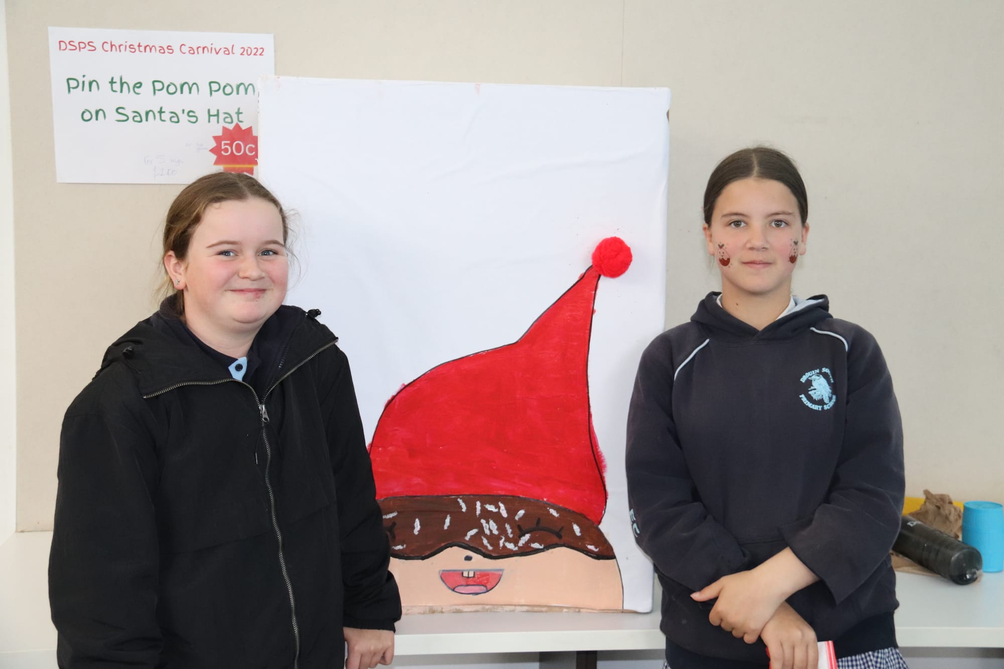 Showing off their 'pin the pom pom on Santa's hat' stall are Bella and Erica.
