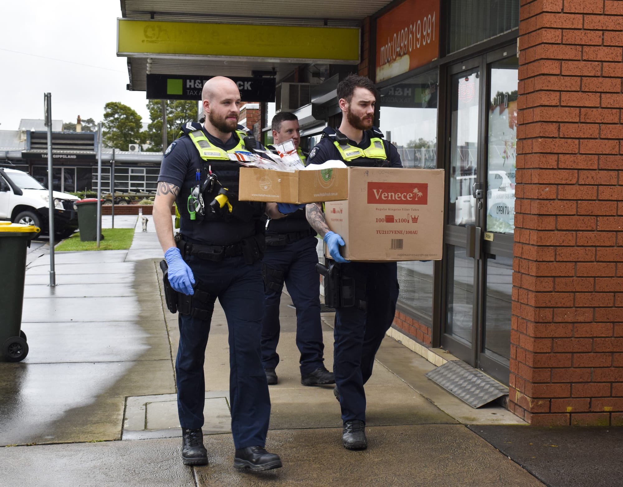 Senior Constable Aaron Bowen, senior constable Colin Smith (behind) and First Constable Riley Hermens remove items from the premisis.