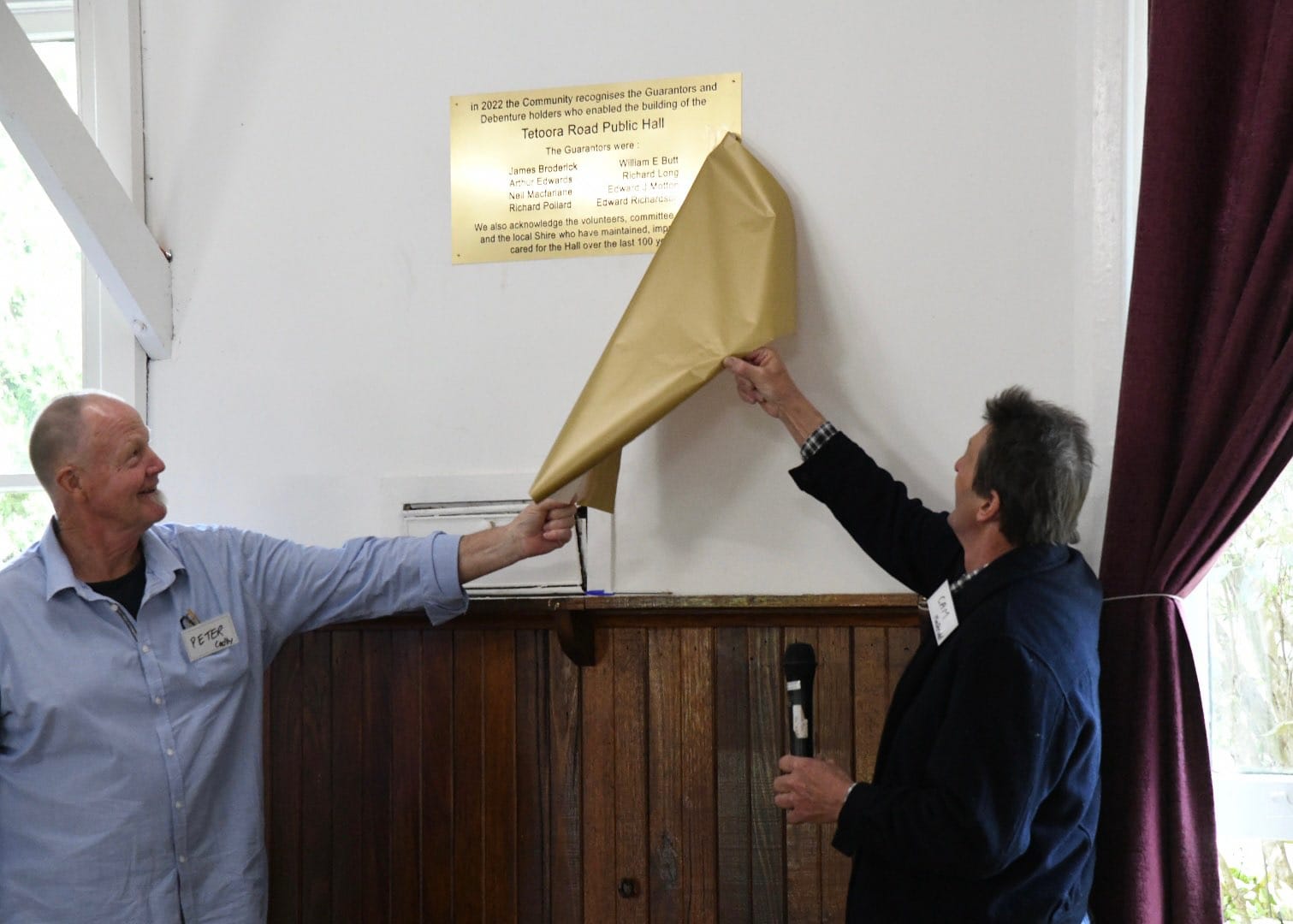 Peter Cadby and Cameron McDonald unveil the plaque that commemorates the eight guarantors the hall's development 100 years ago.
