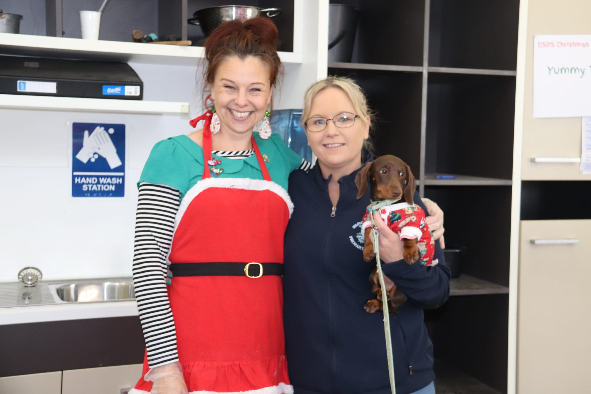 Staff members Anna, Sam and Coco the dog help serve the food indoors.