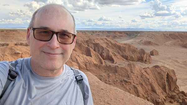 Me blocking the view of red cliffs in a desert