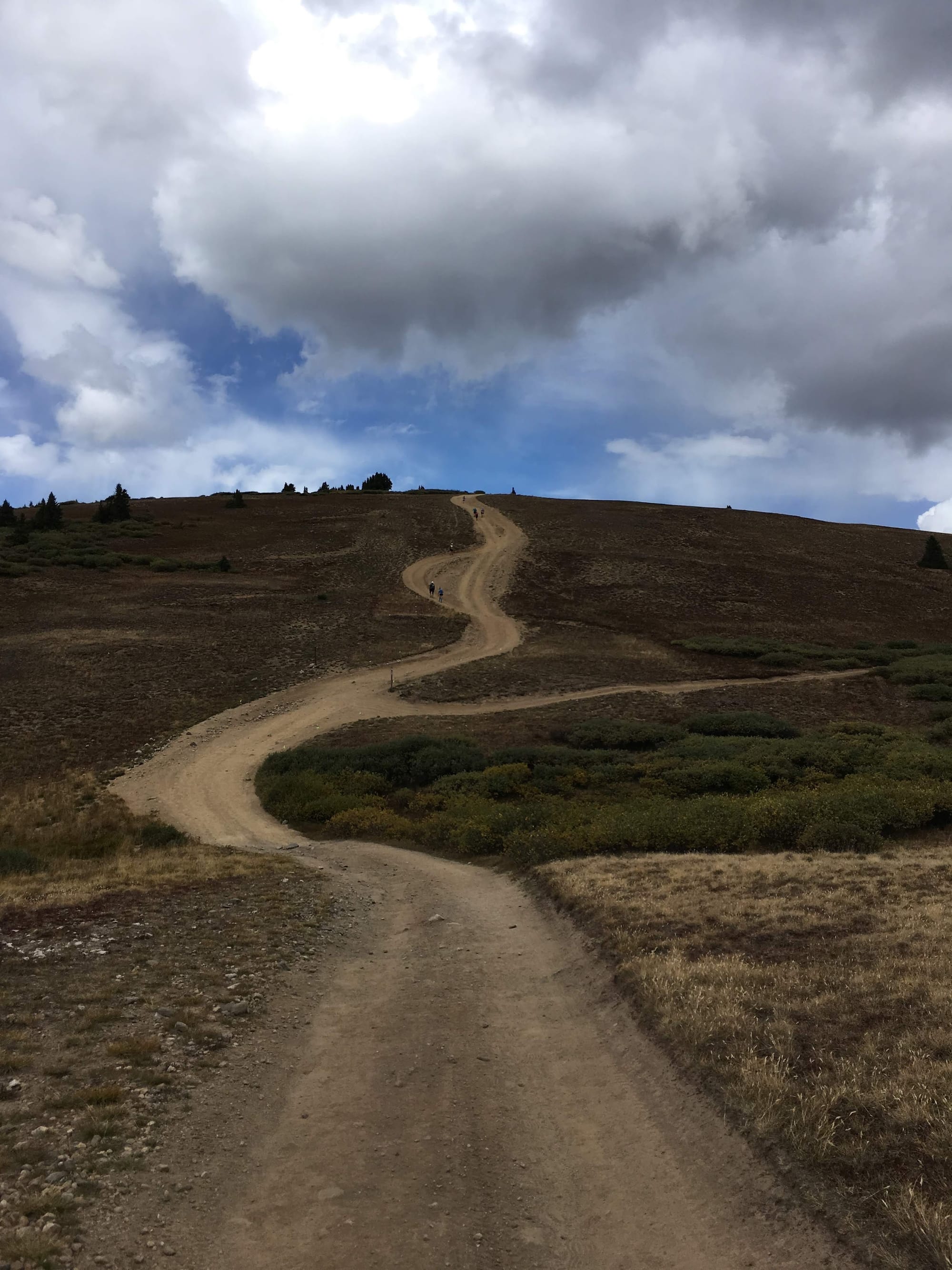 A trail winding up and over a hill into the clouds