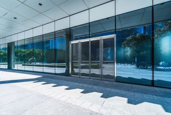 Office entrance with floor to ceiling reflective windows and glass doors. 
