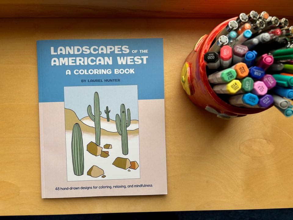 A coloring book by Laurel Hunter and a jar of pens