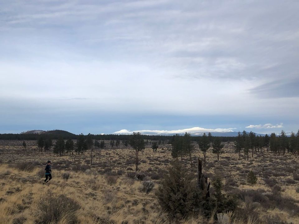The author running on a high desert trail with clouds.